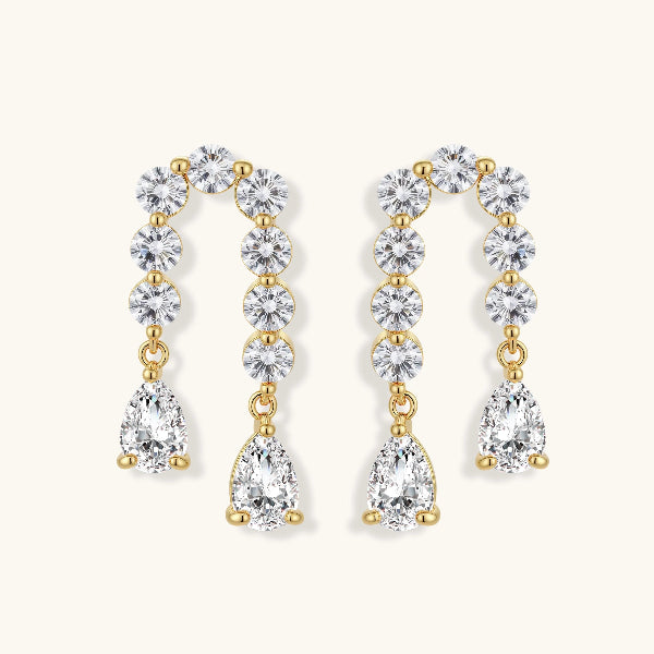 Gold-plated earrings with vertical line of clear crystals and teardrop pendants on neutral background