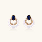 Gold plated stud earrings with an oval lapis lazuli top, CZ-lined teardrop loop and white MOP crescent on a cream background.