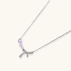 Delicate white gold plated necklace with freshwater pearls and sparkly crystal bow pendant on white background