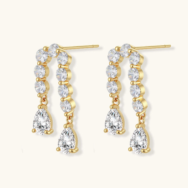 Gold-plated earrings with vertical line of clear crystals and teardrop pendants on neutral background