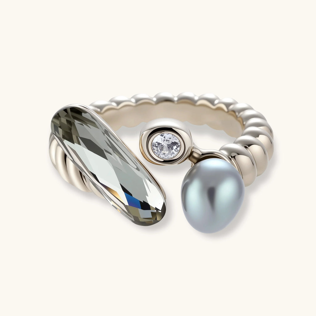 Open-cuff ring in coffee gold with a smoky gray faceted stone, a small zirconia and a gray teardrop bead on a cream background.
