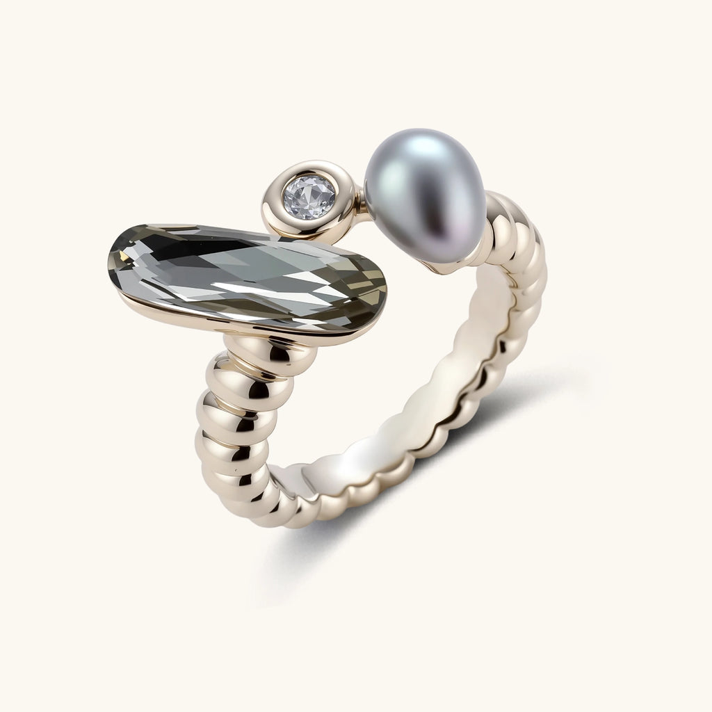 Open-cuff ring in coffee gold with a smoky gray faceted stone, a small zirconia and a gray teardrop bead on a cream background.