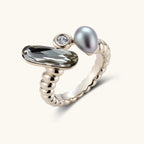 Open-cuff ring in coffee gold with a smoky gray faceted stone, a small zirconia and a gray teardrop bead on a cream background.